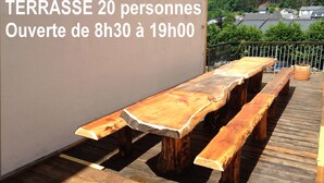Una terraza con mesa y bancos de madera, rodeada por una barandilla.