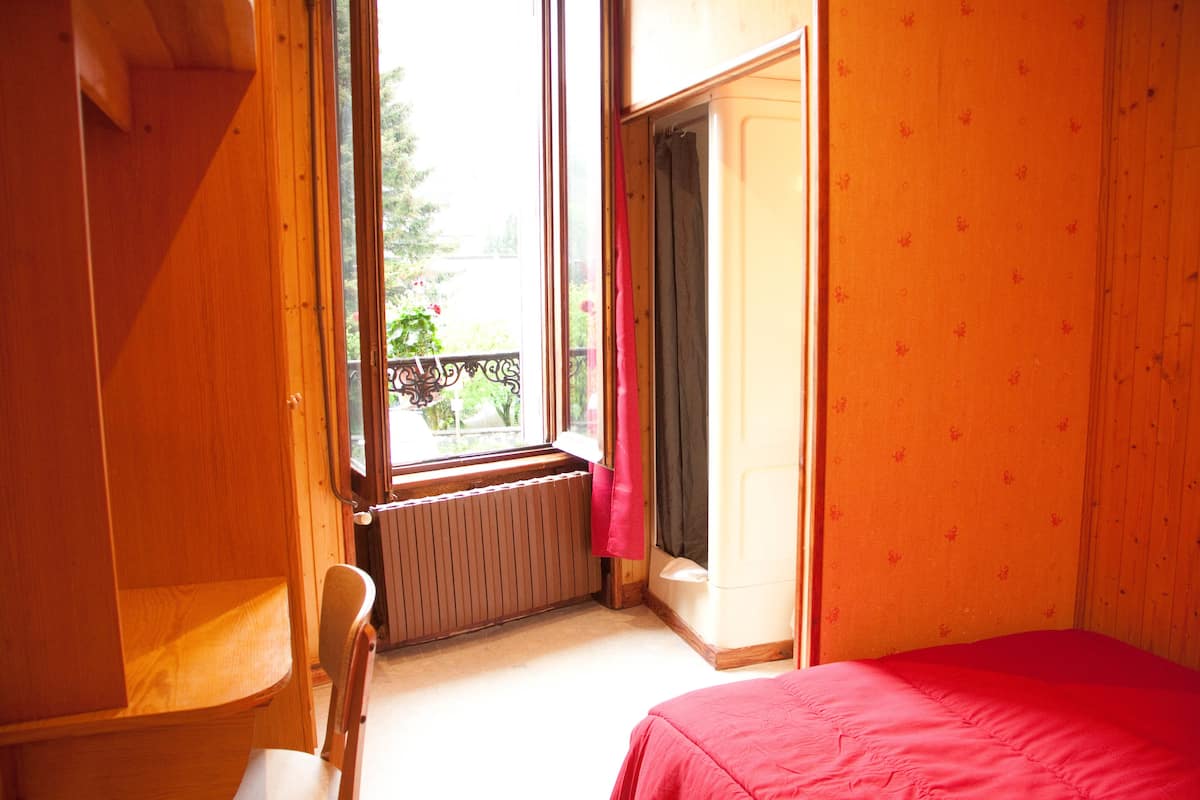 A room with a bed, a chair, a radiator, and a window.