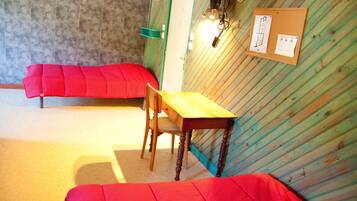 Une pièce avec un bureau en bois, une chaise rouge et un canapé rouge. Un tableau d’affichage avec des papiers est accroché au mur.