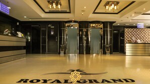 The entrance of the Royal Grand Suite Hotel with a polished floor and a reception desk.