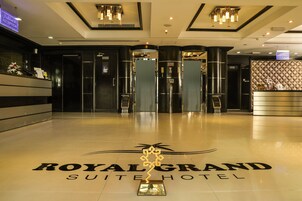 La entrada del Hotel Royal Grand Suite, con piso pulido y un mostrador de recepción.