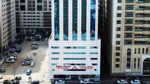 A modern hotel with a prominent vertical design, multiple floors, and a parking lot in front.