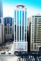 Un hotel moderno con un diseño vertical llamativo, varios pisos y un estacionamiento al frente.