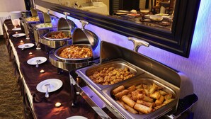 A buffet with various food options, including pasta, fried chicken, and spring rolls.
