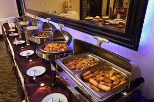 Un bufé con diversas opciones de comida, como pasta, pollo frito y rollos primavera.