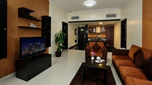 A modern living room with a flat-screen TV, a sofa, a coffee table, and a dining area in the background.