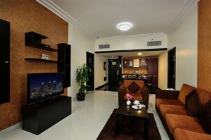 Una sala de estar moderna con una televisión de pantalla plana, un sofá, una mesa de centro y un comedor al fondo.
