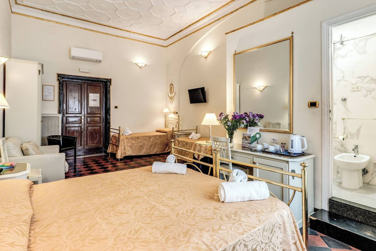 A hotel room with a large bed, a desk, a chair, a vanity with a mirror, and a bathroom with a sink and mirror.