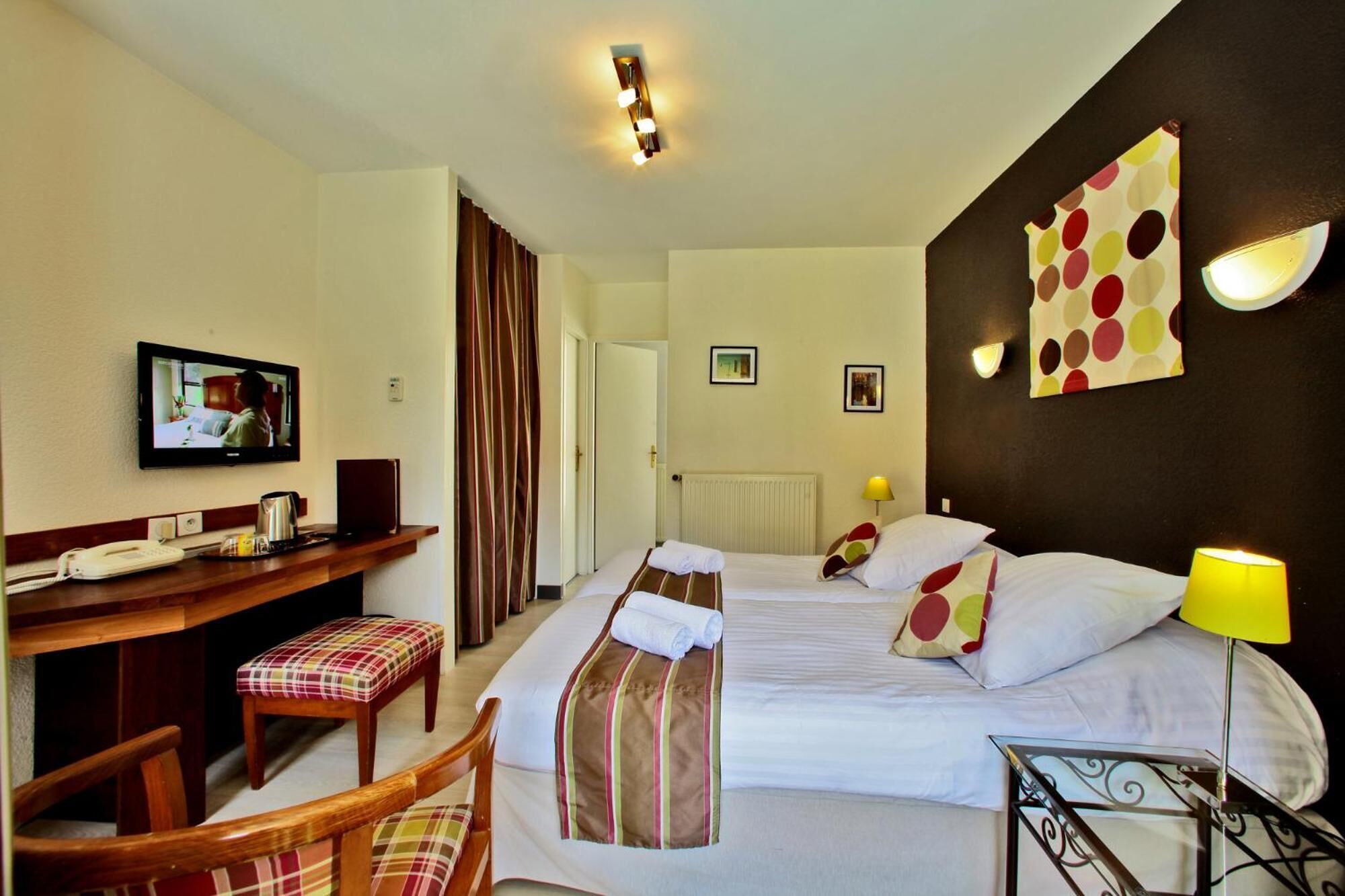 Habitación de hotel con dos camas, un escritorio, un teléfono, una televisión y una silla.