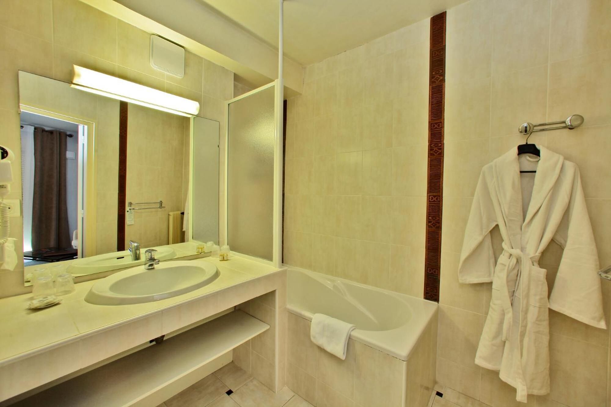 A modern bathroom with a large mirror, a sink, a bathtub, and a robe hanging on a towel rack.