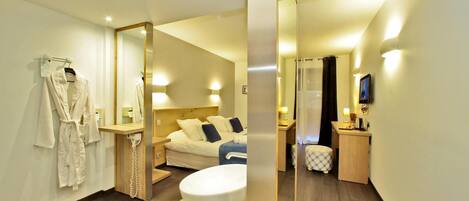 A modern hotel room with a large bed, a bathroom with a bathtub, and a small desk area.