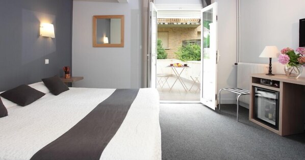 Un hotel moderno con una cama grande, un escritorio pequeño con lámpara y vistas al patio exterior.