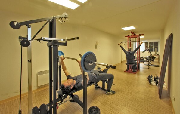 A gym with various exercise equipment, including a bench press and a squat rack.