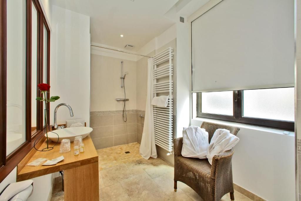 Une salle de bain équipée d’un lavabo, d’un miroir, d’une douche et d’une chaise en osier avec des serviettes.