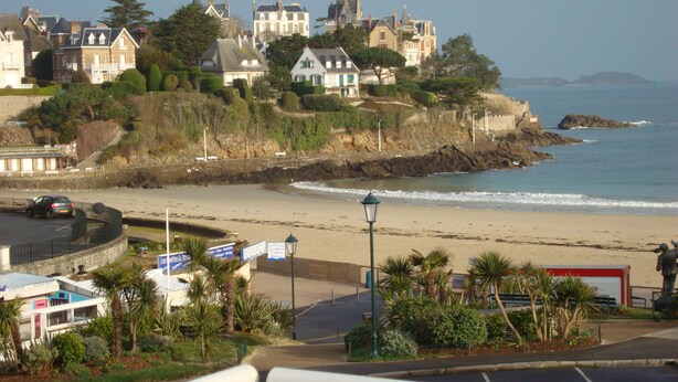 A coastal town with historic buildings, a beach, and a road with signs. - Hotel de la Plage (Dinard)