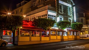 A hotel with a balcony, a restaurant with a red neon sign, and a sign for 'Hotel Plage'. - Hotel de la Plage (Dinard)
