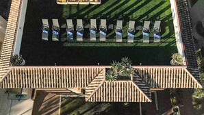 An aerial view of a hotel with a rooftop terrace, rows of chairs, and potted plants. - apartamentos Albir Confort (L'Alfas del Pi)