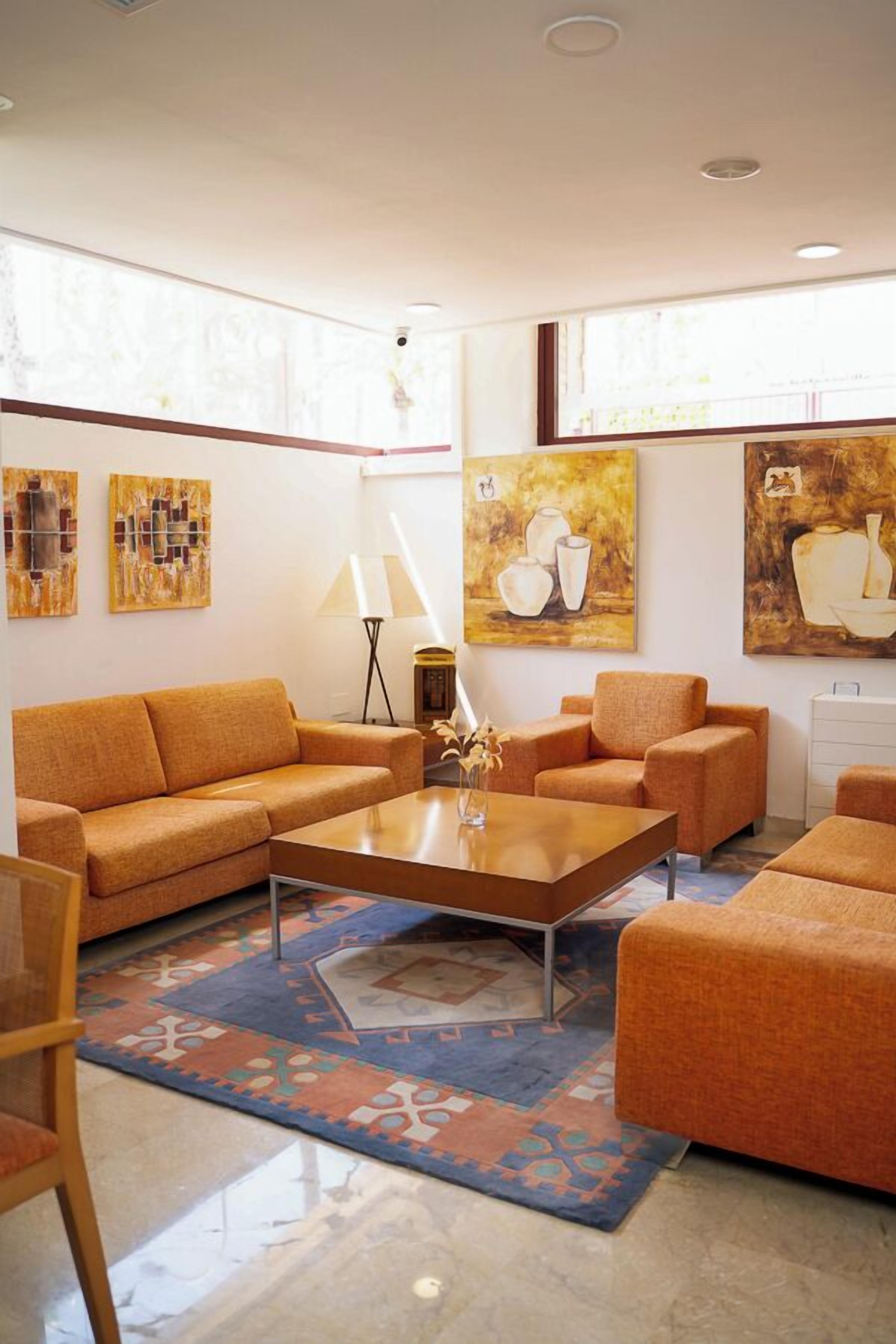 A modern living room with orange sofas, a coffee table, and abstract paintings on the walls.