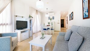 A modern living room with a grey sofa, a white coffee table, and a flat-screen TV on a white cabinet. - apartamentos Albir Confort (L'Alfas del Pi)
