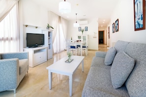Apartamento premium, 1 quarto | Área de estar | TV de tela plana, livros