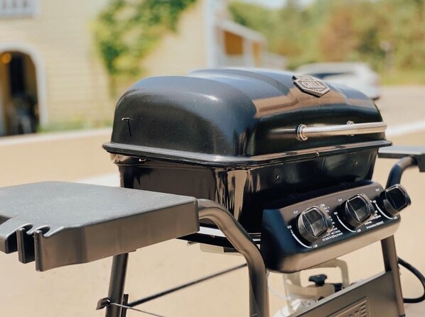 A portable gas grill with a lid, control knobs, and a side table. - Ephraim Motel (Ephraim)