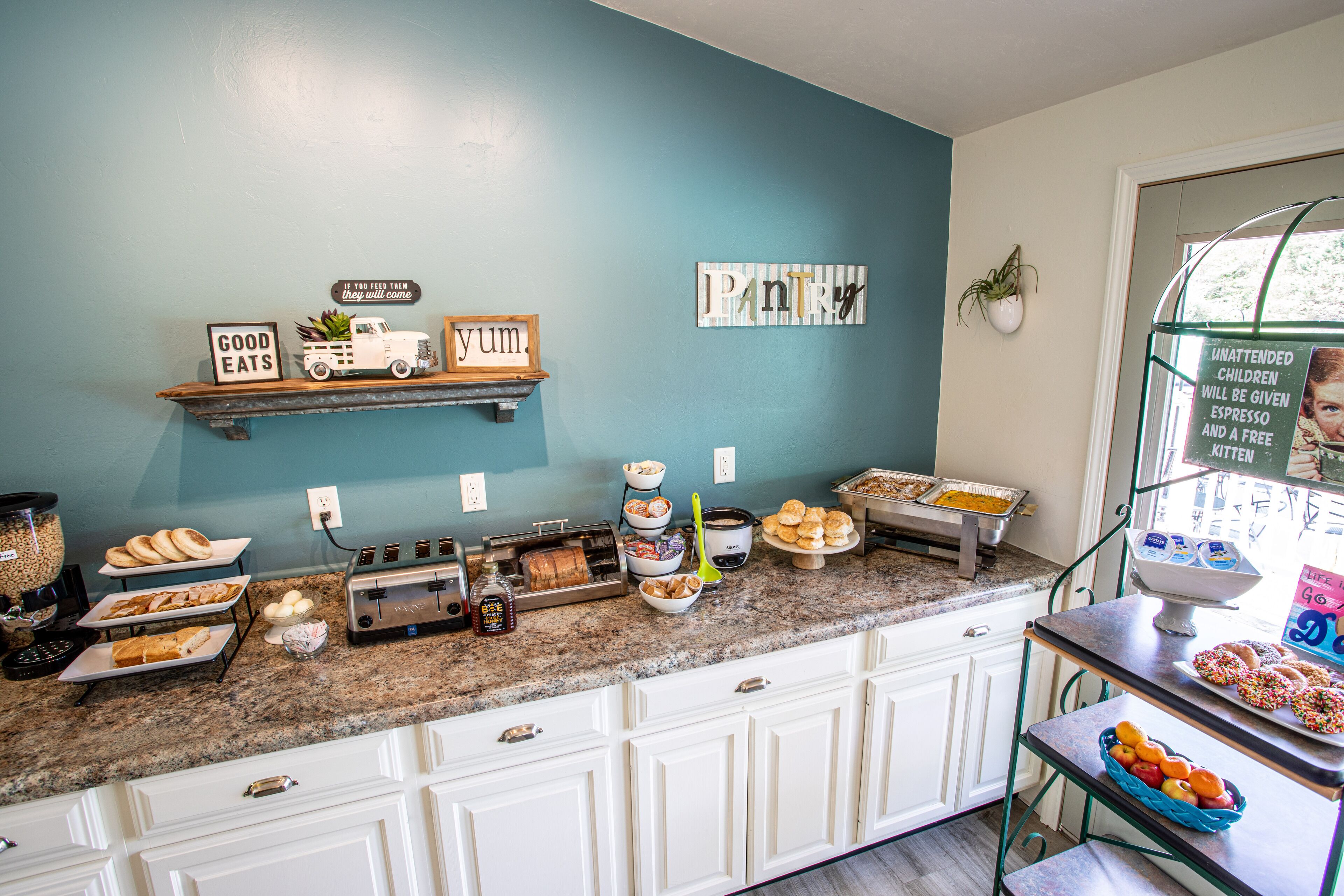 Una cocina con pared azul, armarios blancos y diversos alimentos sobre la encimera.