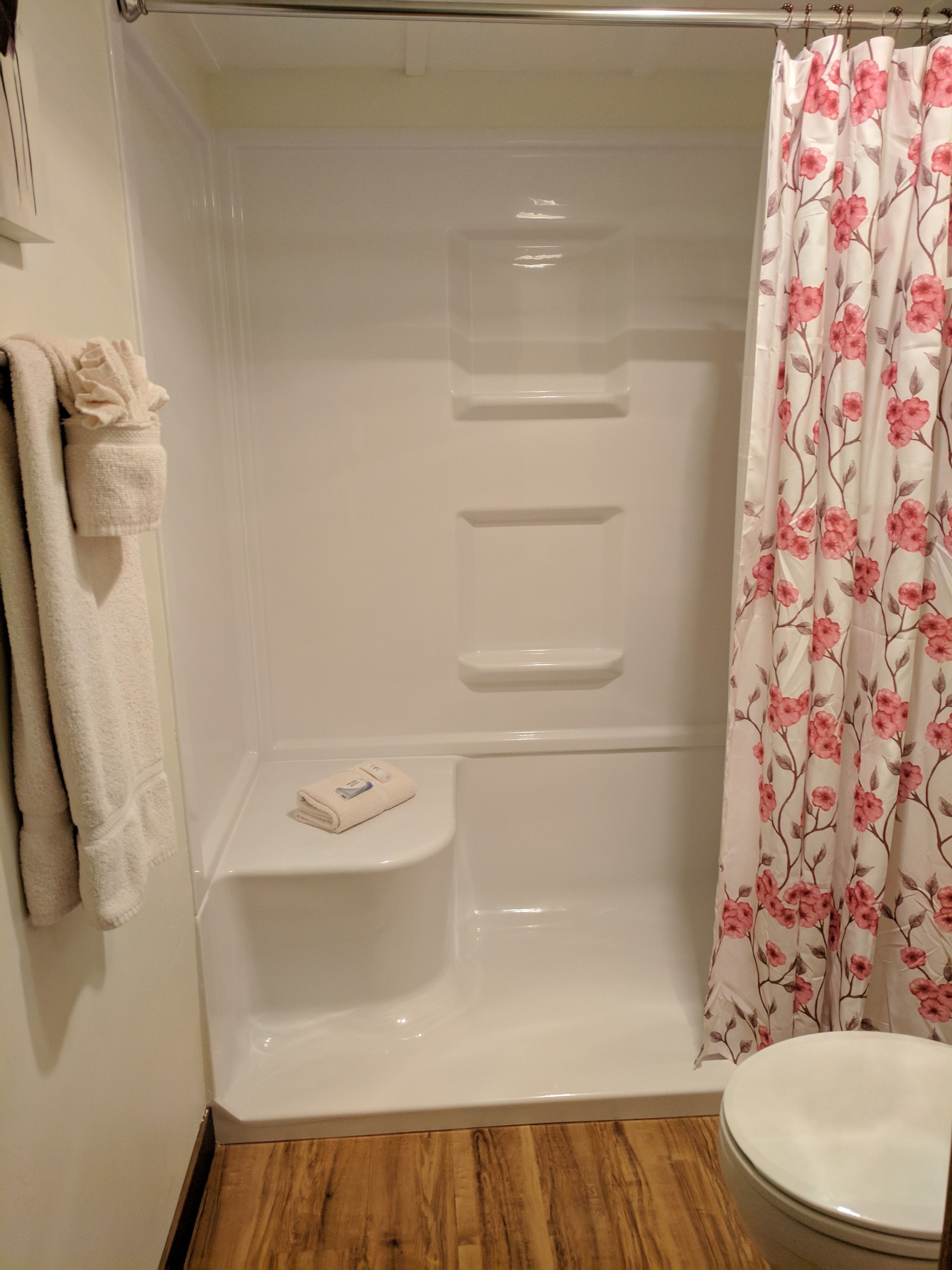 Ein Badezimmer mit Dusche, Toilette und Handtuchhalter mit Handtüchern.