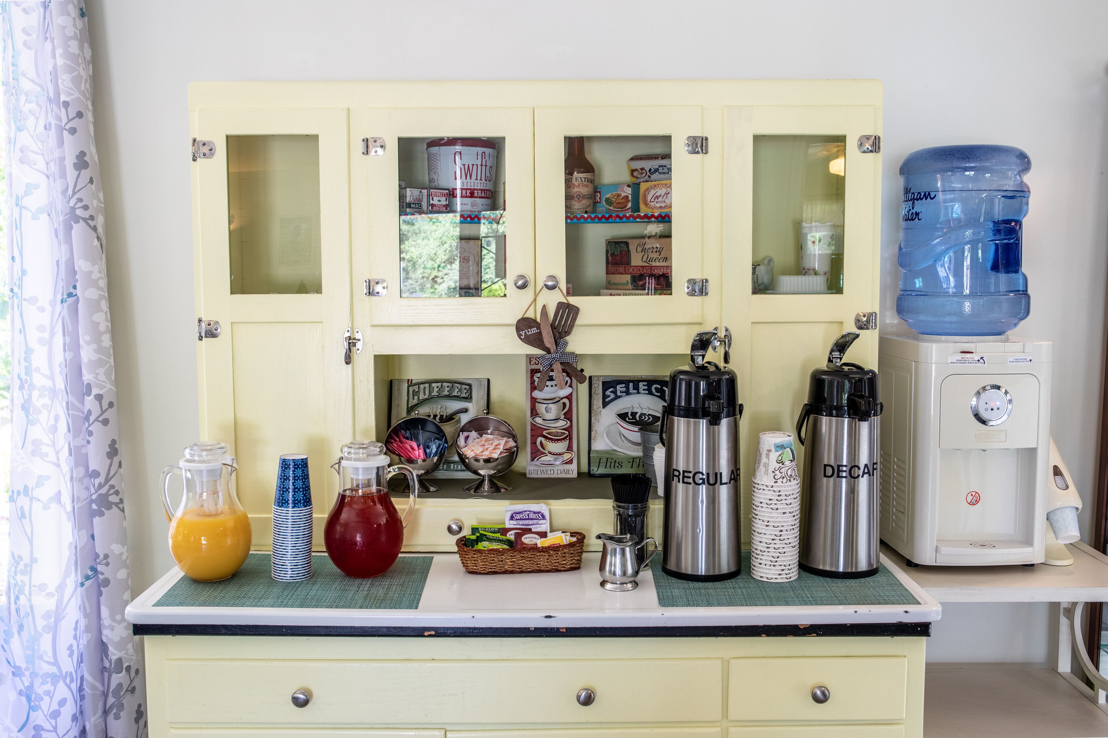 A kitchen counter with a water dispenser, coffee maker, and various kitchen items.