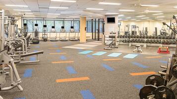 A gym with various exercise equipment, including treadmills, weight machines, and free weights.
