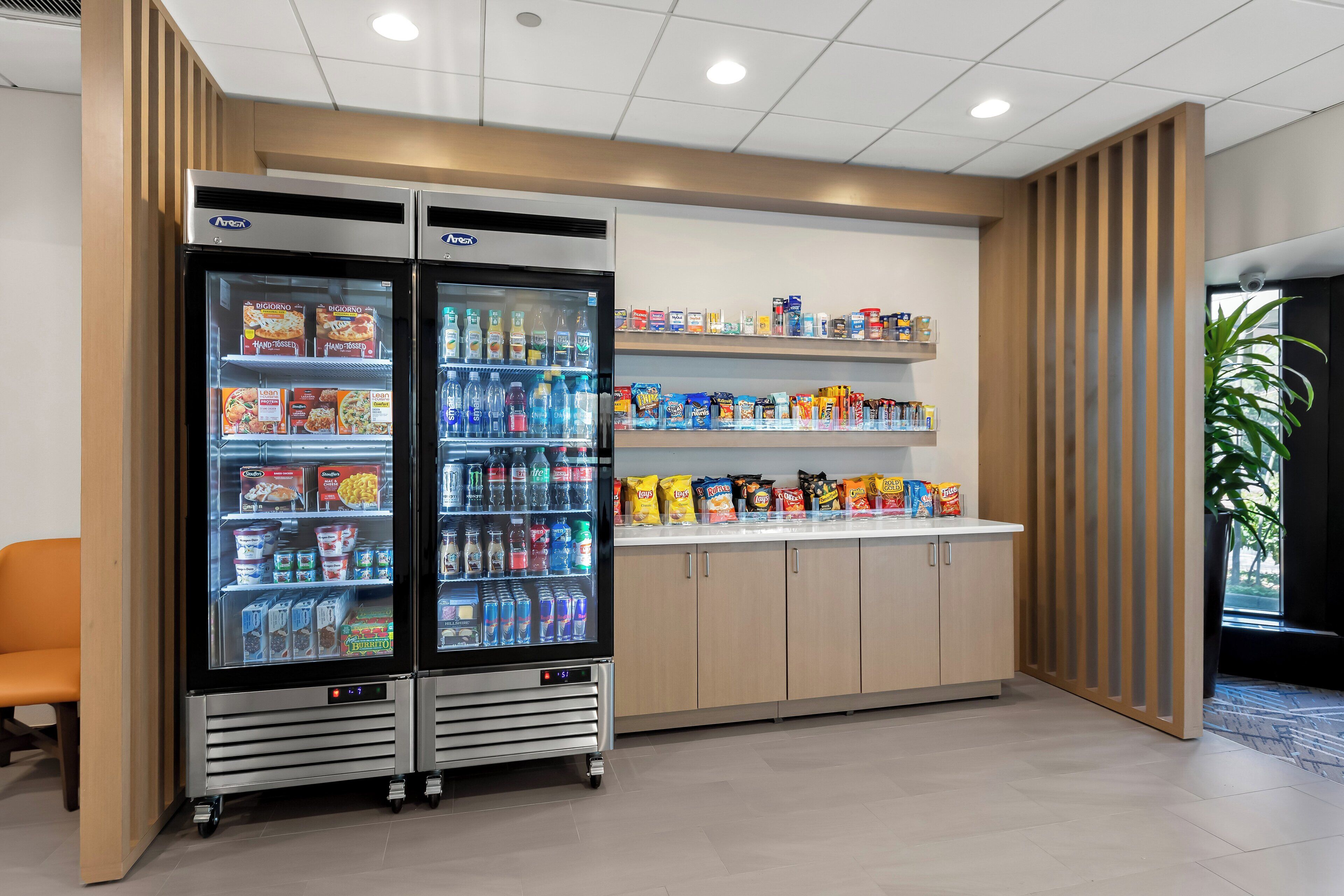 A vending area with two refrigerated beverage dispensers and shelves stocked with snacks and beverages.