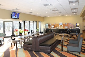 A restaurant with a bar, seating area, and a television screen.