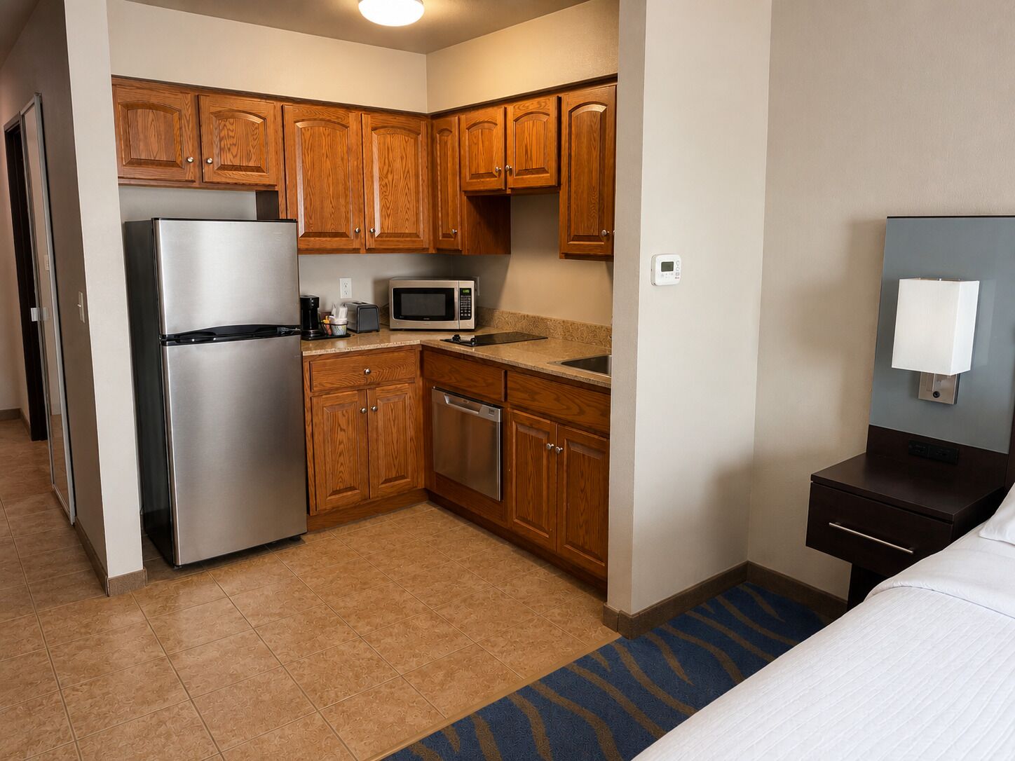 A compact hotel room with a kitchenette, including a refrigerator, microwave, and dishwasher.