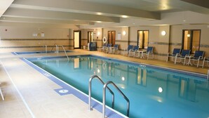 Una piscina d'hotel amb una vista lateral extensa, que inclou una cadira de socorrista, gandules i un espai per als canvis.