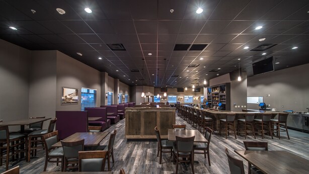 Un restaurant ampli amb diverses zones de menjador, una barra central i un disseny de sostre modern.