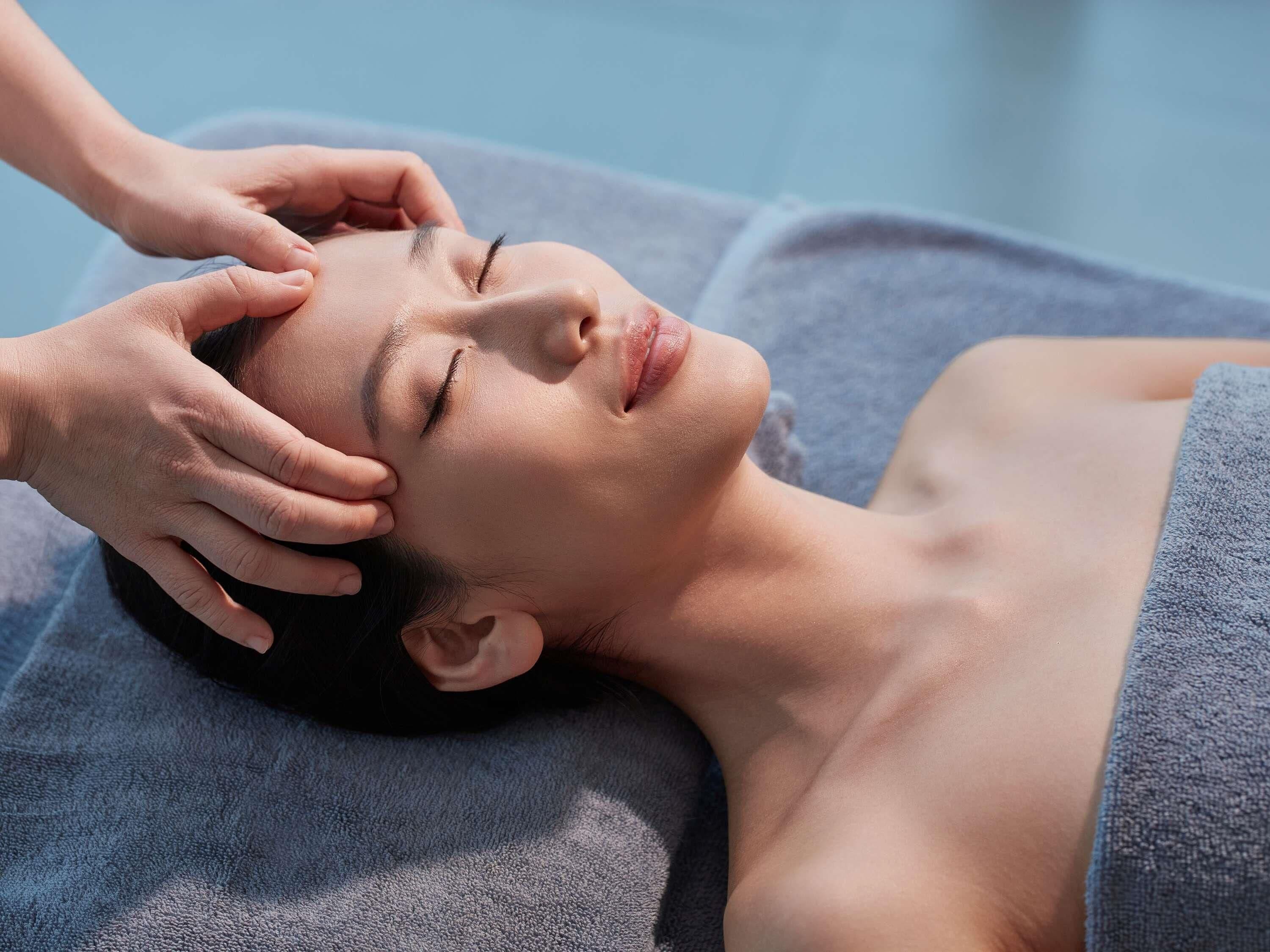 A person lying on a massage table with a towel covering their lower body.
