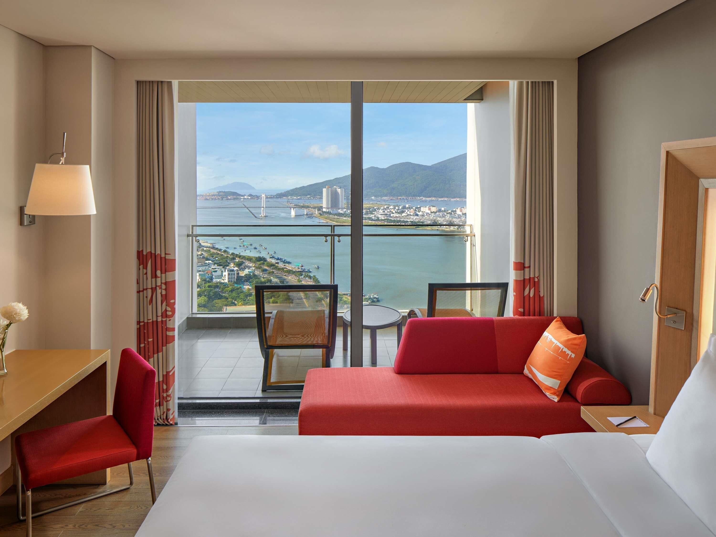 Een hotelkamer met balkon, een bed, bureau en stoel.