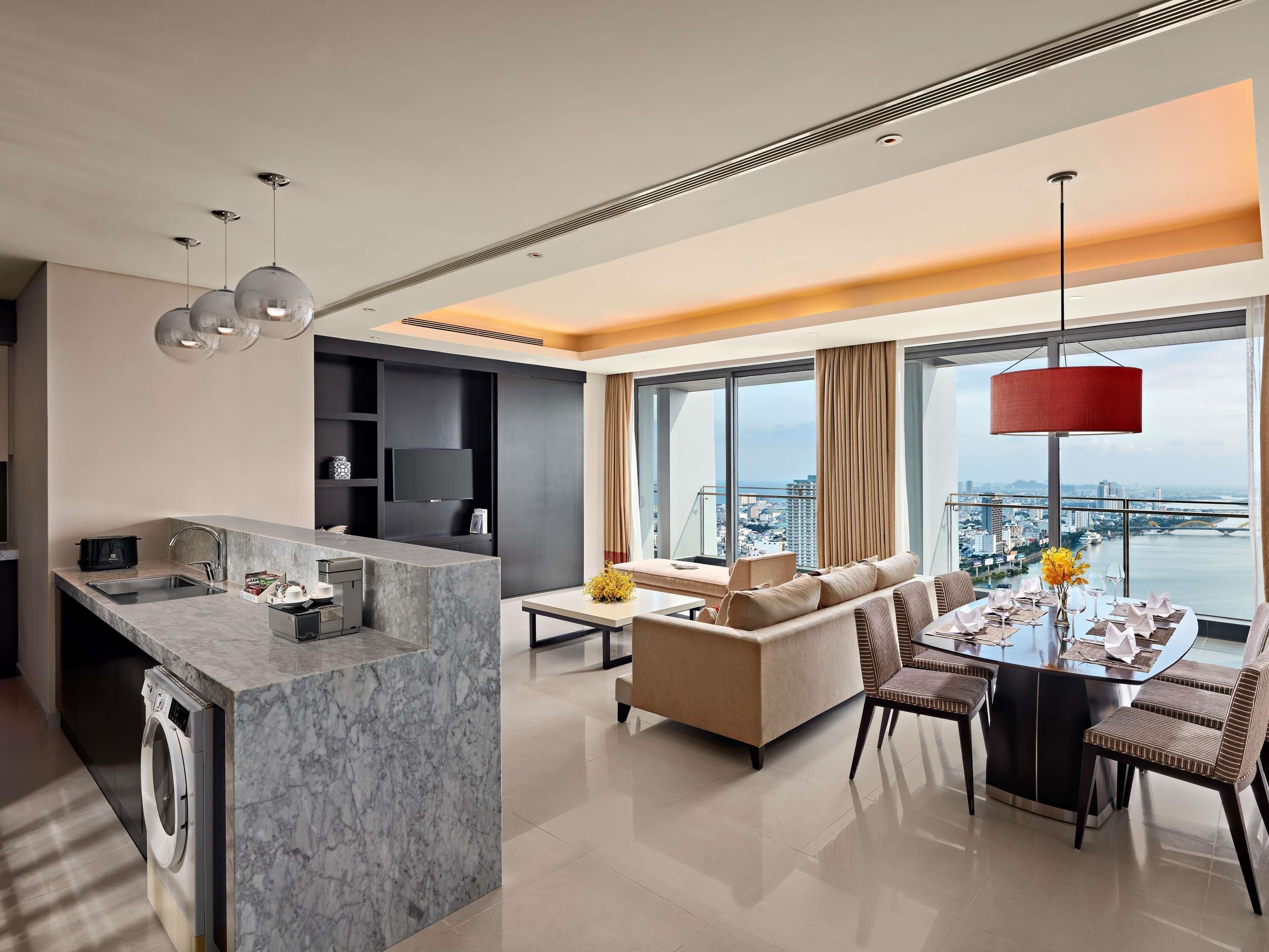 A modern living space with a kitchen, dining area, and seating by a large window overlooking a cityscape.