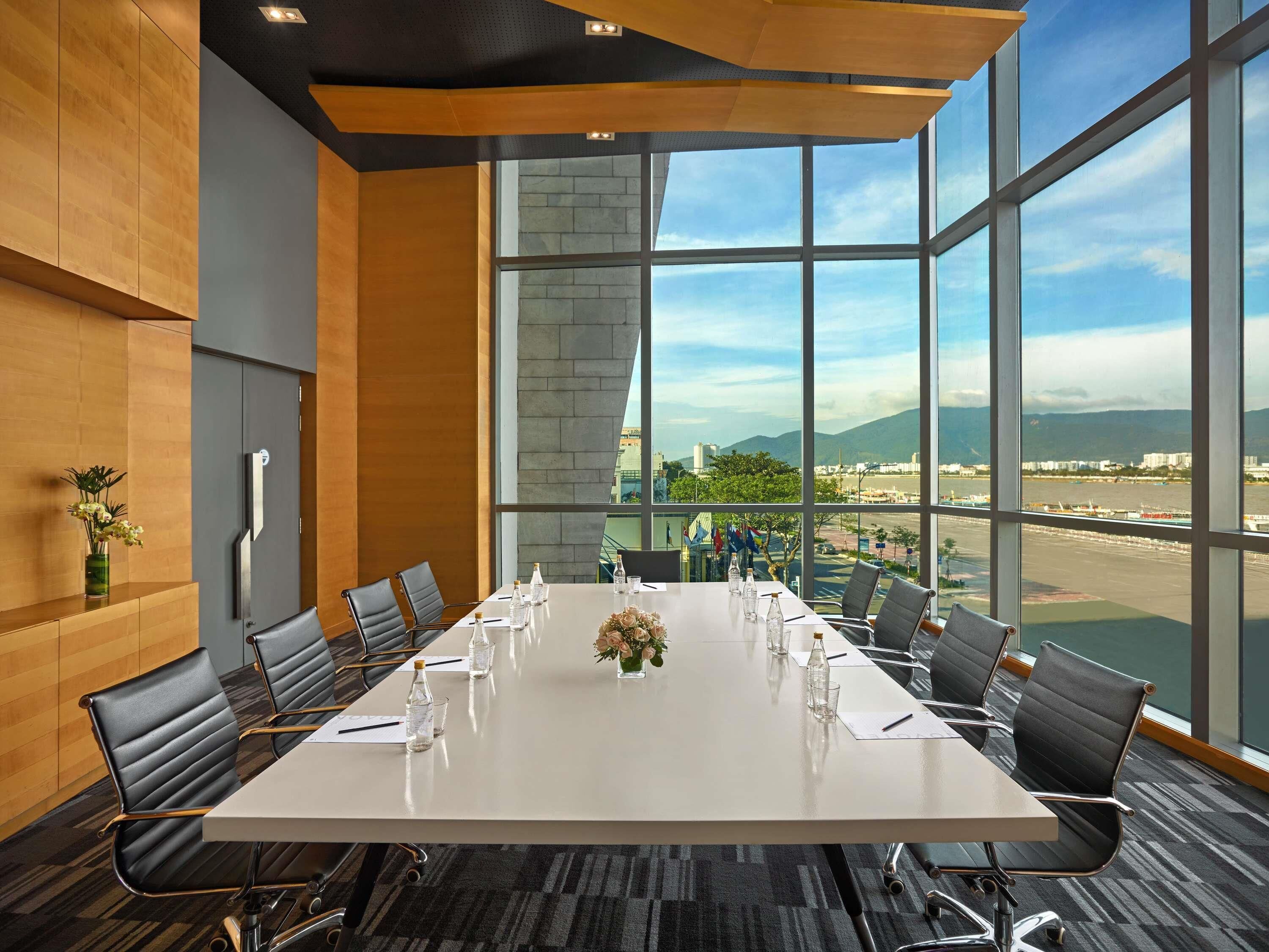 Une salle de conférence avec une longue table, des chaises et une vue sur un aéroport.