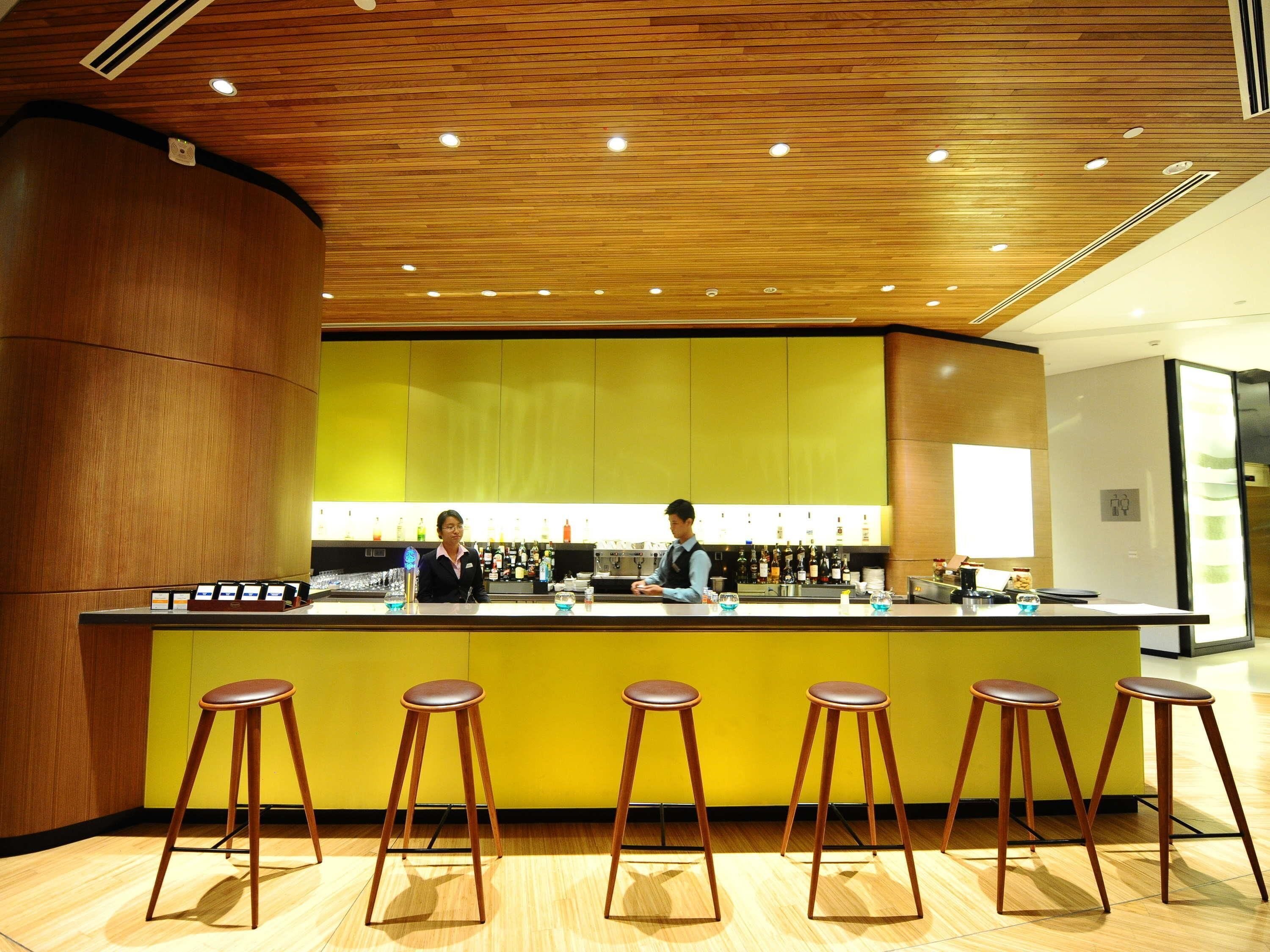 A bar area with wooden ceiling, yellow walls, and wooden stools.