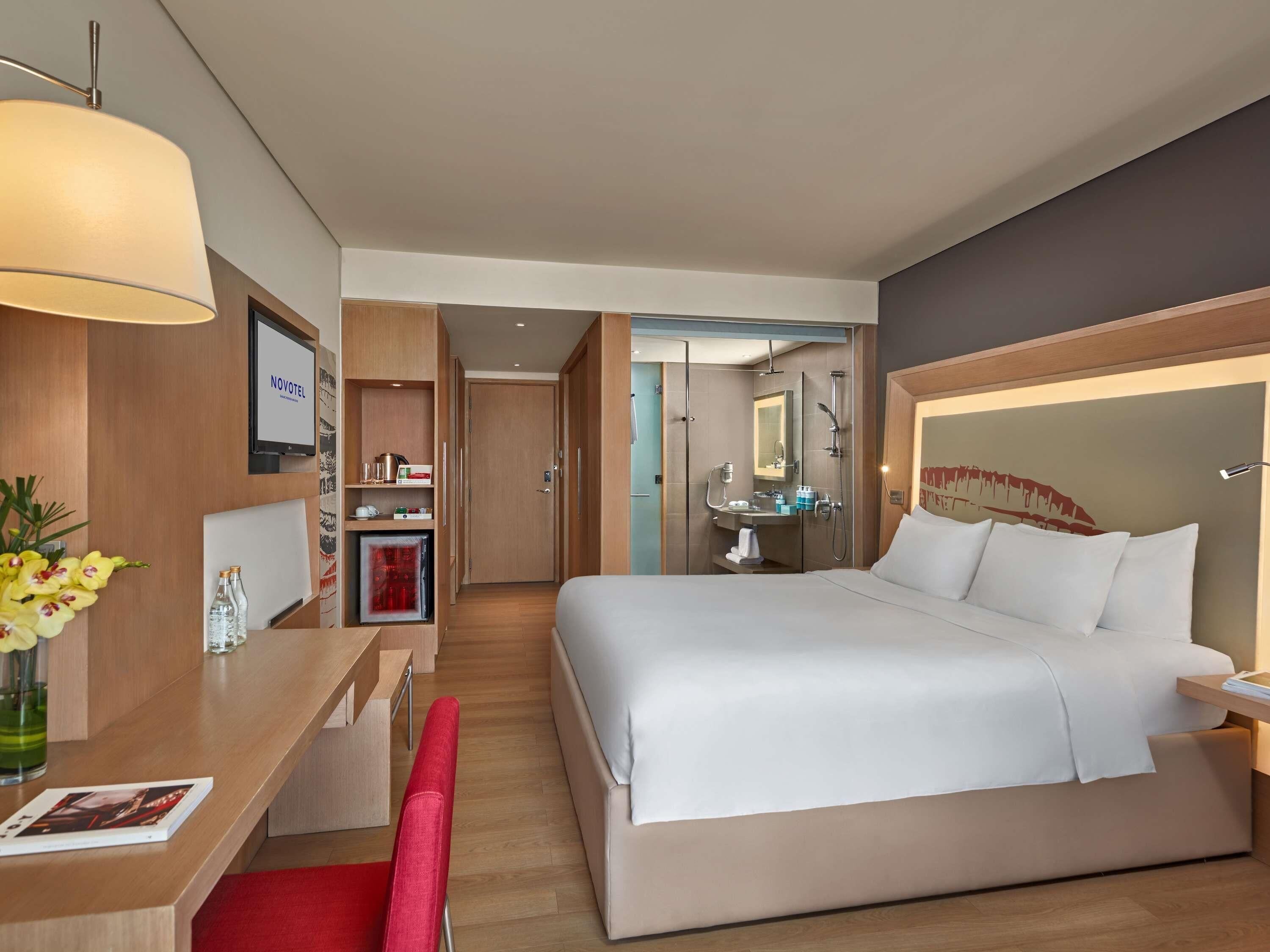 Una habitación de hotel con cama, escritorio, silla y baño con ducha y lavamanos.