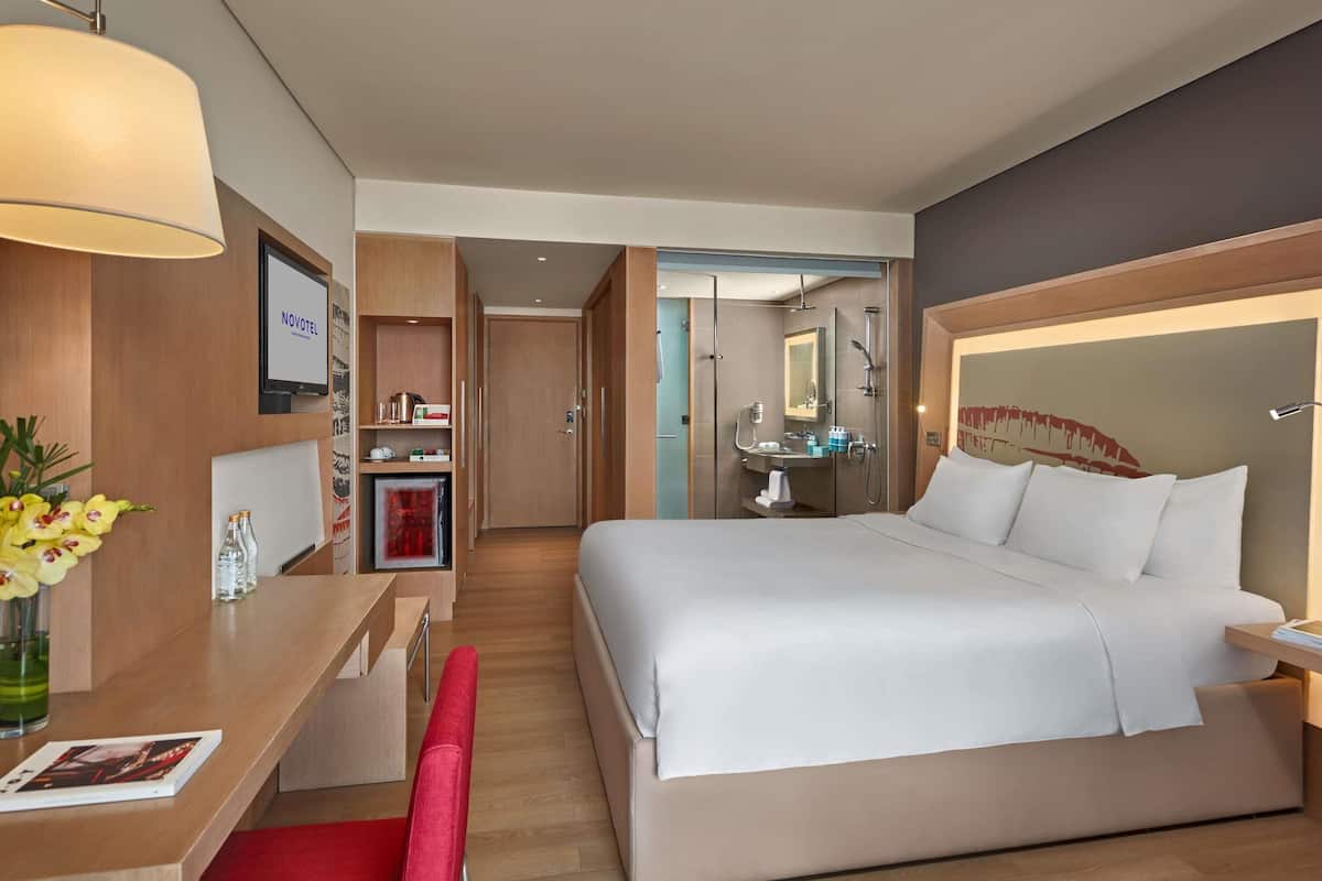 Una habitación de hotel con cama, escritorio, silla y baño con ducha y lavamanos.
