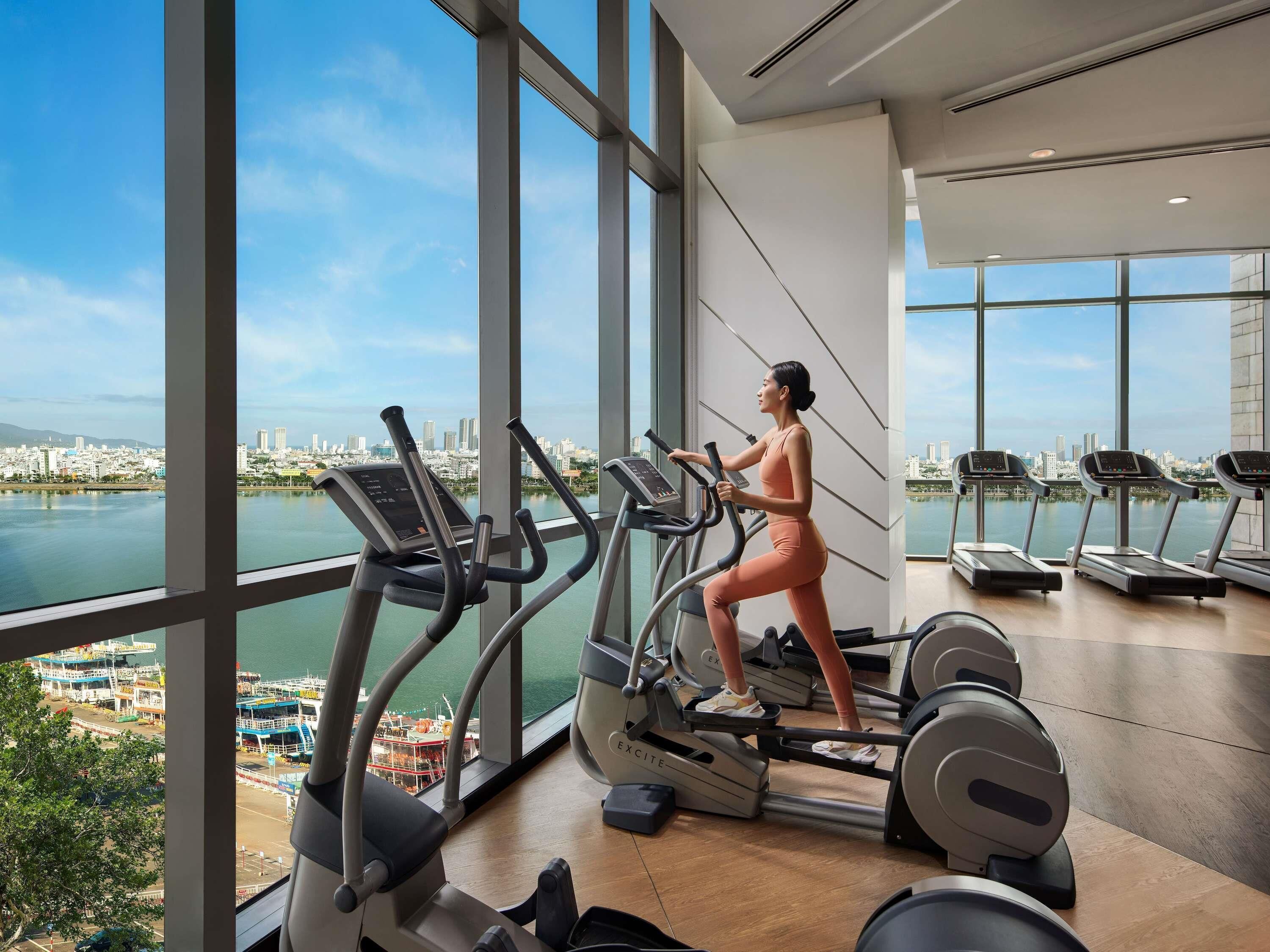 A gym with large windows, a city view, and exercise equipment.