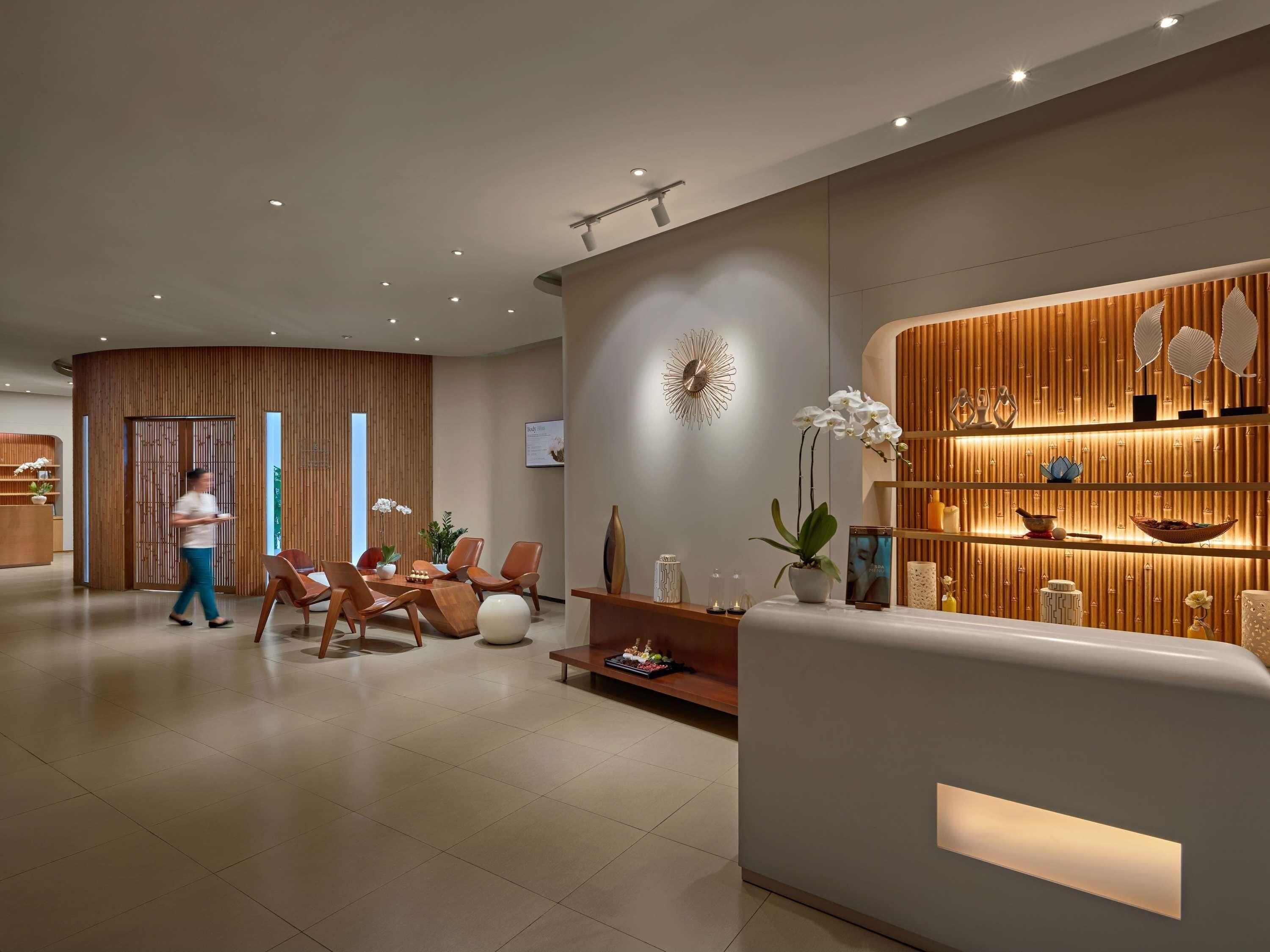 Un área de recepción moderna con un mostrador de madera, zona de estar con sillas, un adorno en la pared y una recepción.