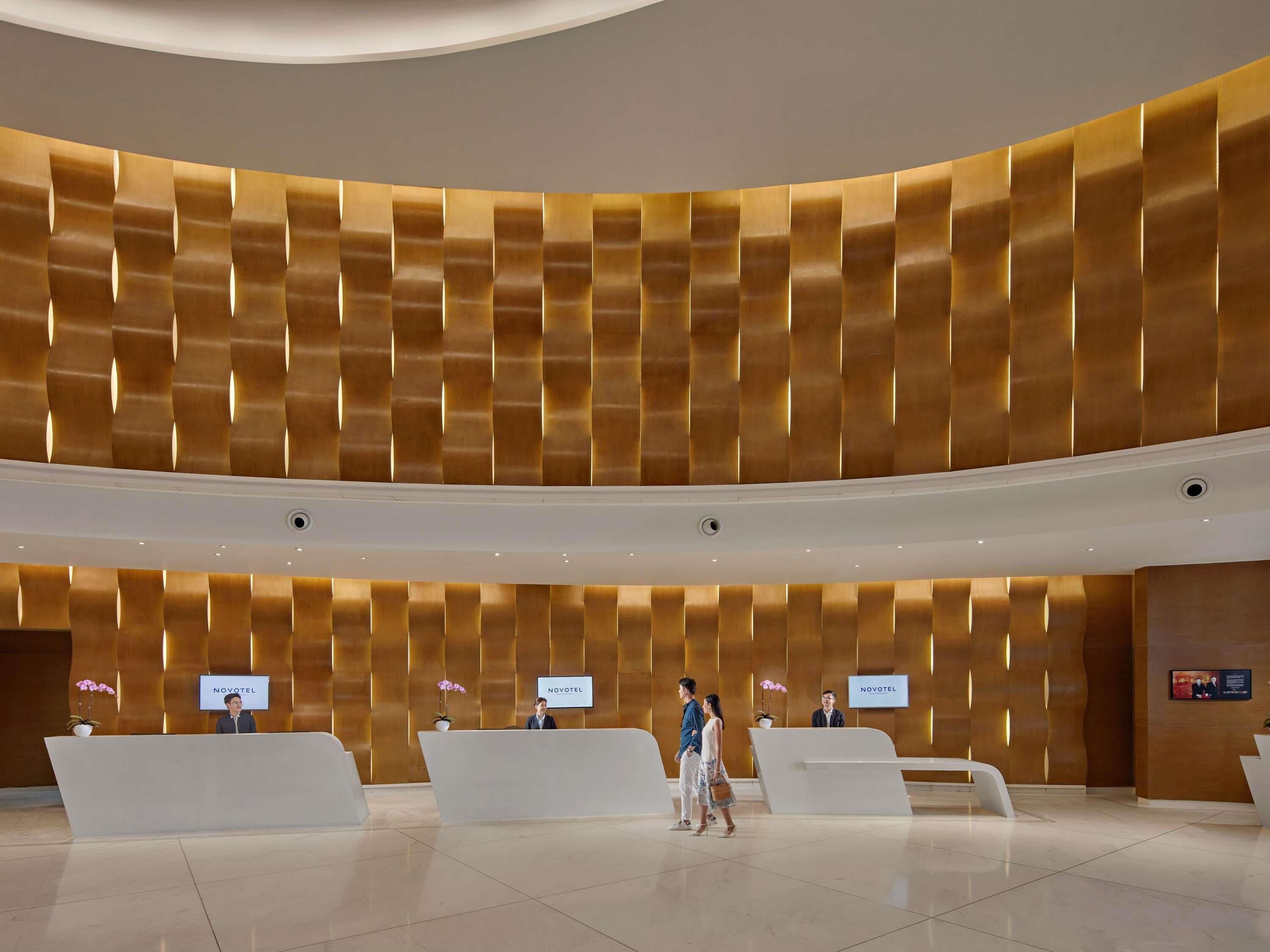 A modern hotel lobby with a curved ceiling, reception desks, and a clean, polished floor.