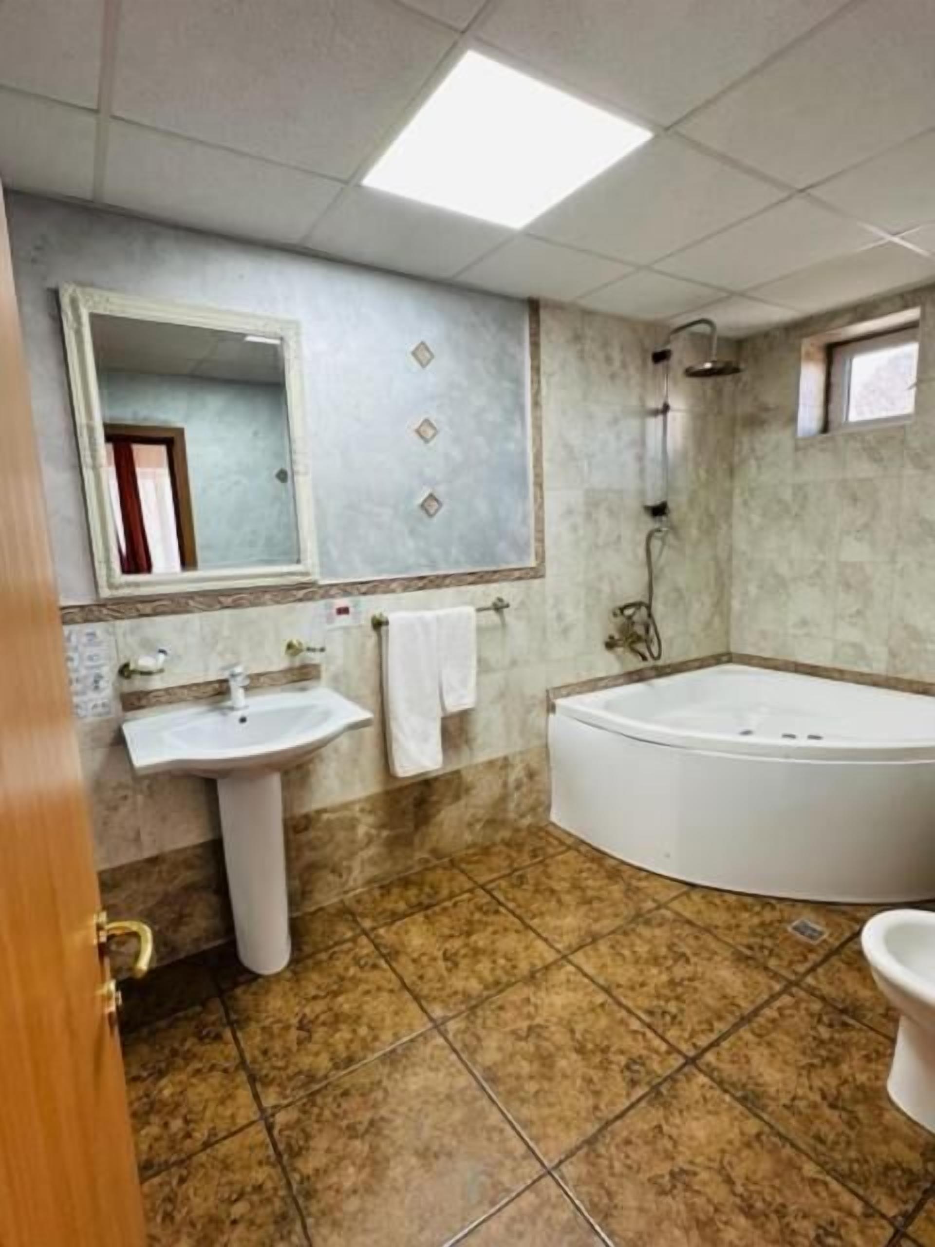 Een badkamer met een wastafel, spiegel en bad.