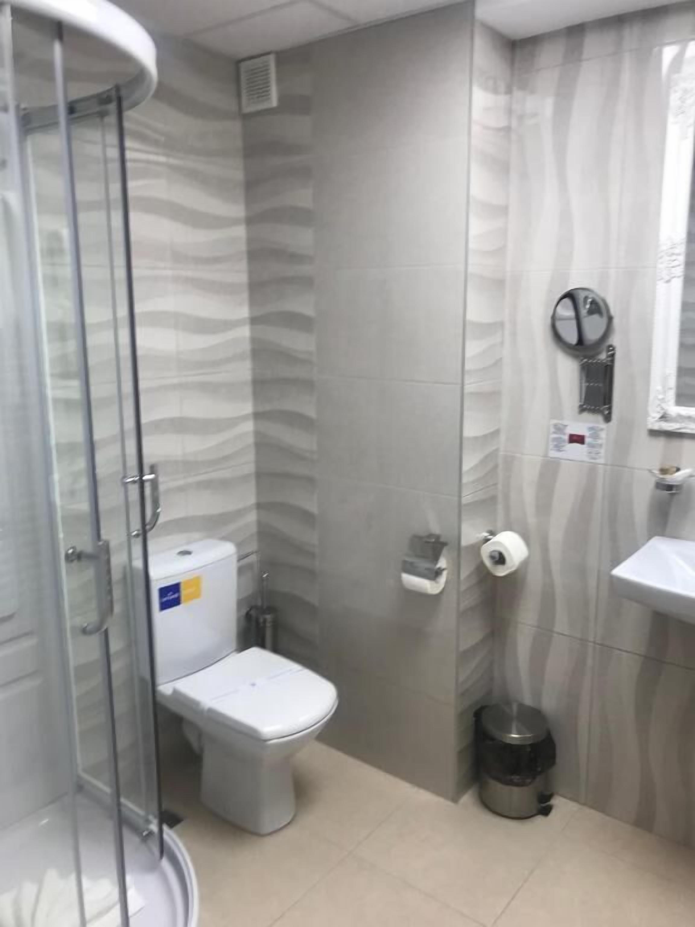 Ein Badezimmer mit Toilette, Waschbecken, Mülleimer und einer Duschkabine.