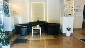 A lobby with a black leather sofa, a small white table, and a decorative floor pattern. - Bulevard Prestige Hotel (Slatina)