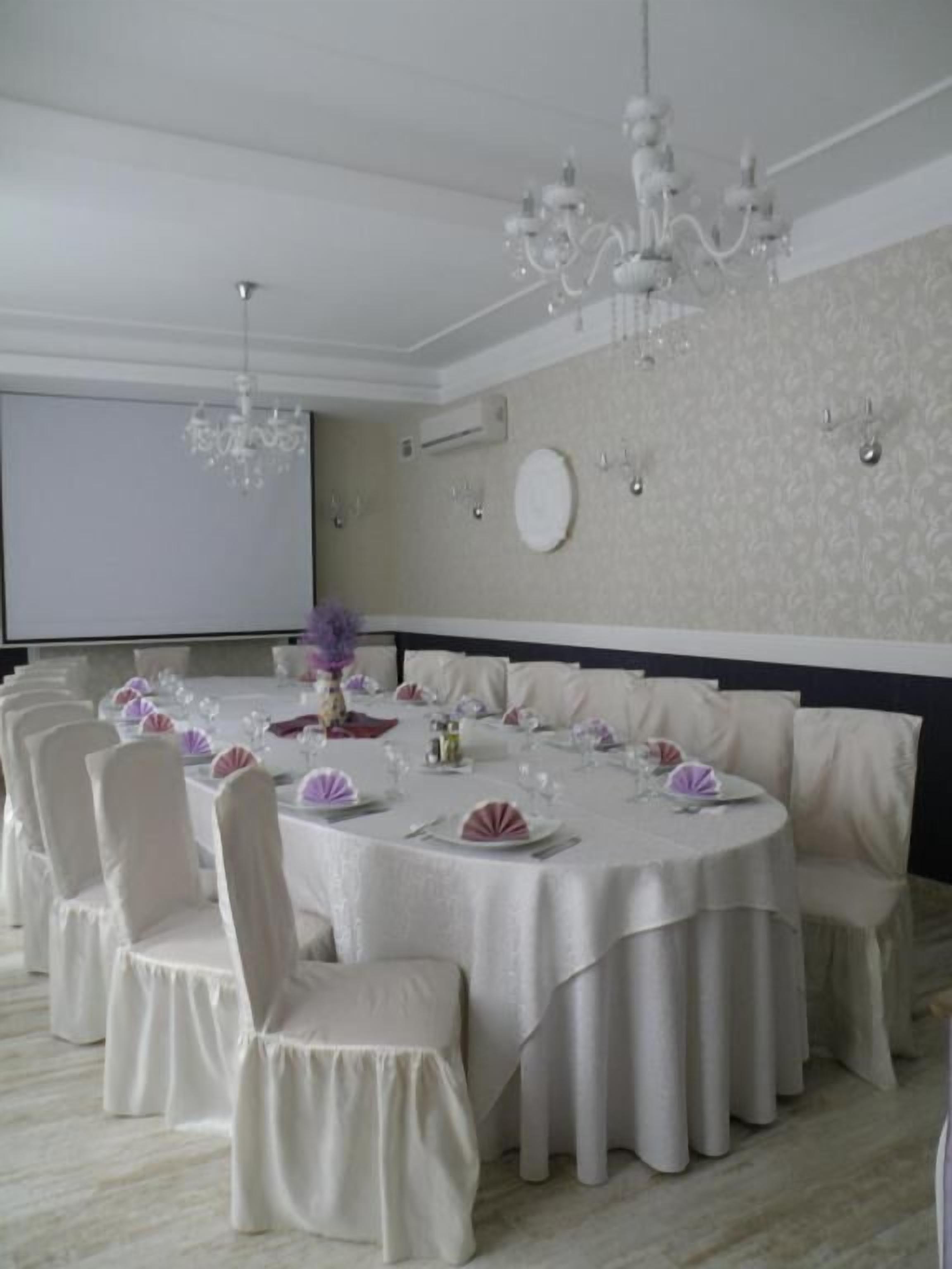 Un comedor formal con mesas redondas, manteles blancos y sillas a juego.