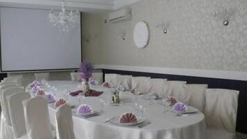 Un comedor formal con mesas redondas, manteles blancos y sillas a juego.