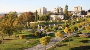 A park with pathways, trees, and buildings in the background. - Bulevard Prestige Hotel (Slatina)